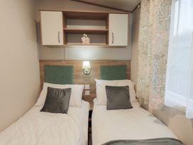 A bedroom with two single beds and a shelf at Caravan