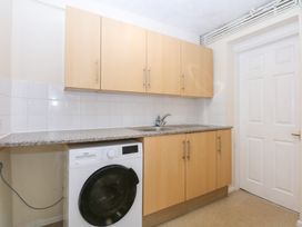 A kitchen with a washing machine and cabinets at Canning Lodge in Colwyn Bay