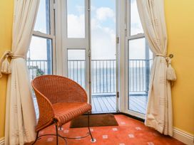 A balcony with a chair and sliding door at Val's Seaview in Ilfracombe