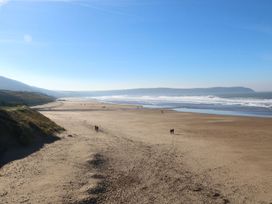 A beach with waves and people walking at Val's Seaview in Ilfracombe