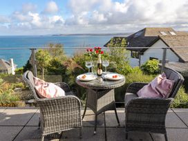 A balcony with a table and chairs overlooking the sea at 2 Remera in St. Ives