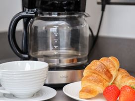 A coffee maker with a cup and saucer next to croissants and strawberries at 2 Remera St. Ives