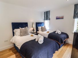 A bedroom with two beds and a bedside lamp at 2 Remera St. Ives