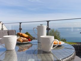 A table with cups and a teapot on a balcony at 2 Remera St Ives