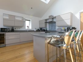 A kitchen with modern appliances and bar stools at 2 Remera St Ives