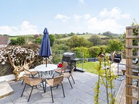 A garden with a table and chairs and a barbecue grill at Orchard View in St. Austell