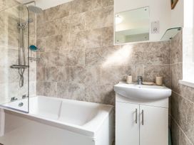 A bathroom featuring a bathtub, shower, sink, and mirror at Orchard View, St. Austell