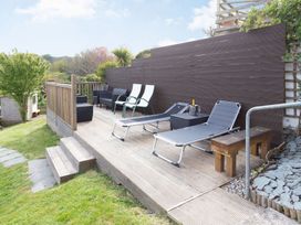 An outdoor area with lounge chairs and a table at Orchard View in St. Austell