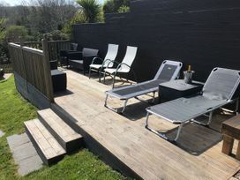 An outdoor space with lounge chairs and a coffee table at Orchard View St. Austell