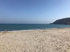 A beach with sand, water, and people at Orchard View in St. Austell