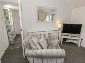 A living room with an armchair and television at Falconers Cottage
