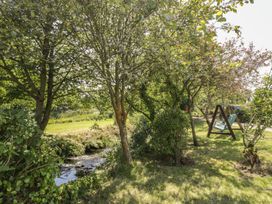 A garden with trees and a stream at Falconers Cottage