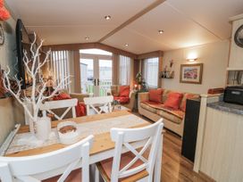 A living room with a dining table and sofa at Beachside in Towyn