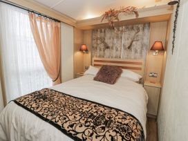 A bedroom with bed and curtains at Beachside in Towyn