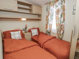 A bedroom with two beds and a bedside table at Beachside in Towyn