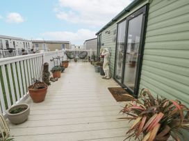 An outdoor deck with potted plants and chairs at Beachside in Towyn