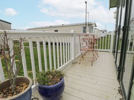 A balcony with chairs and plant pots at Beachside in Towyn