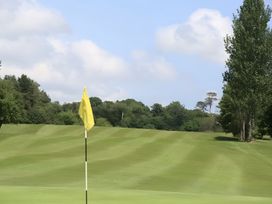 A golf course with a yellow flag and trees at The Rocks in Newry