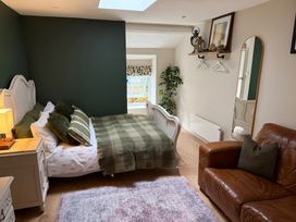 A bedroom with a bed and brown couch at Studio Apartment at High Dyke Farm, Cockermouth