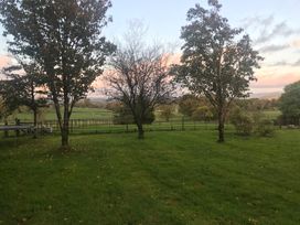 A grassy area with trees and a fence at Studio Apartment at High Dyke Farm Cockermouth