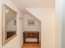 A hallway with a wooden table, mirror and wall hooks at Greenham Rise in Norton-Sub-Hamdon