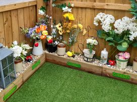 A garden corner with decorative flowers, pots, and a lantern at Greenham Rise Norton-Sub-Hamdon