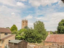A view of a church tower surrounded by trees and buildings at Greenham Rise Norton-Sub-Hamdon