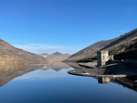 A lake surrounded by mountains with a building at 87 Ballyveaghmore Road Newry