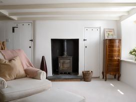 A living room with a stove and wooden cabinet at The Cottage in Helston