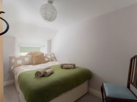 A bedroom with a bed and chair at The Cottage in Helston