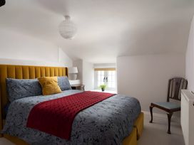 A bedroom featuring a bed, chair and lamp at The Cottage in Helston