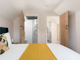 A bedroom with a bed and doors leading to a bathroom at The Cottage in Helston