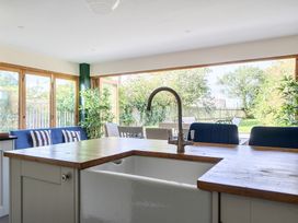 A kitchen with a sink and bar stools at The Cottage in Helston