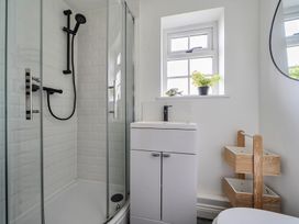 A bathroom with a shower, sink, and storage at The Cottage in Helston