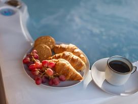A plate with croissants, cookies, grapes, and a coffee cup by a hot tub