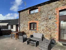 An outdoor seating area with stone wall and hot tub at Granary Barn in Winkleigh