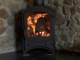 A stove with fire in a living room at Granary Barn in Winkleigh