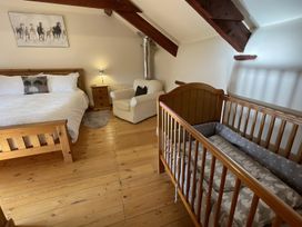A bedroom with a bed, crib, and sofa at Granary Barn in Winkleigh