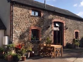 An outdoor area with a wooden table and plants at Granary Barn in Winkleigh