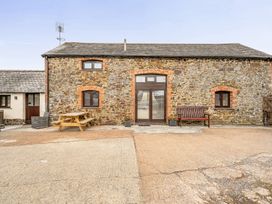 An outdoor area with a stone building and seating arrangements at Granary Barn Winkleigh