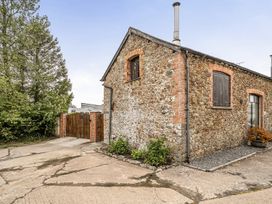 An outdoor view of a stone building with a wooden gate at Granary Barn Winkleigh