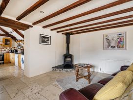 A living room with a wood burner and kitchen units at Granary Barn Winkleigh