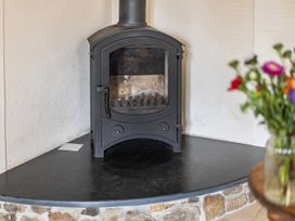 A wood stove with a stone base in the living room at Granary Barn Winkleigh