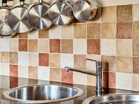 A kitchen with a sink and metal pots hanging above the counter at Granary Barn in Winkleigh