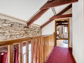 A hallway with wooden railing and stone wall at Granary Barn in Winkleigh