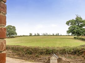 A view of a field with trees and a dog house at Granary Barn in Winkleigh