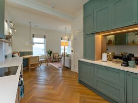 A kitchen with cabinets and a dining area at Seafront Apartment in Donaghadee