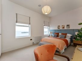 A bedroom with a bed, bedside table, and window at Seafront Apartment in Donaghadee