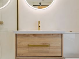 A sink and vanity with a faucet and mirror at Seafront Apartment in Donaghadee