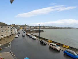 A view showing cars parked along a road by the water at Seafront Apartment in Donaghadee